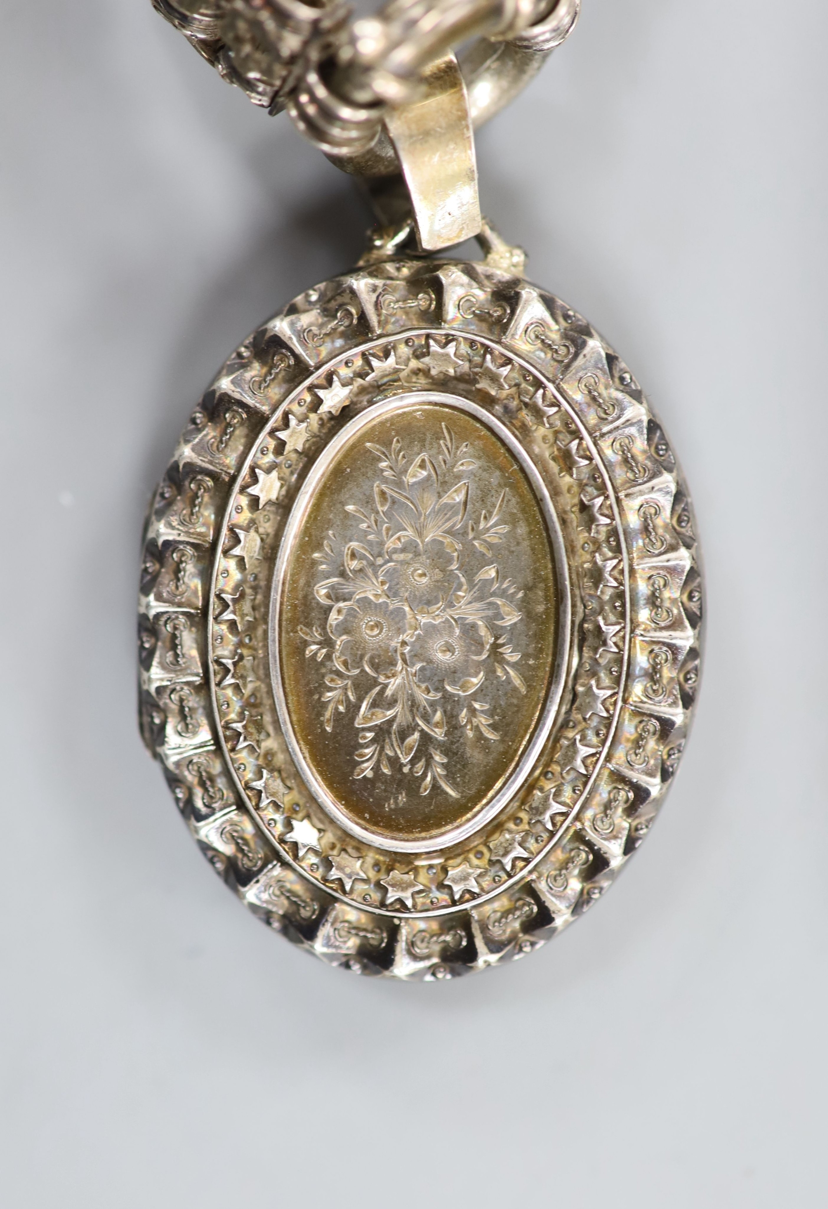 A late Victorian silver oval locket, 45mm, on a pierced white metal chain, 43cm.